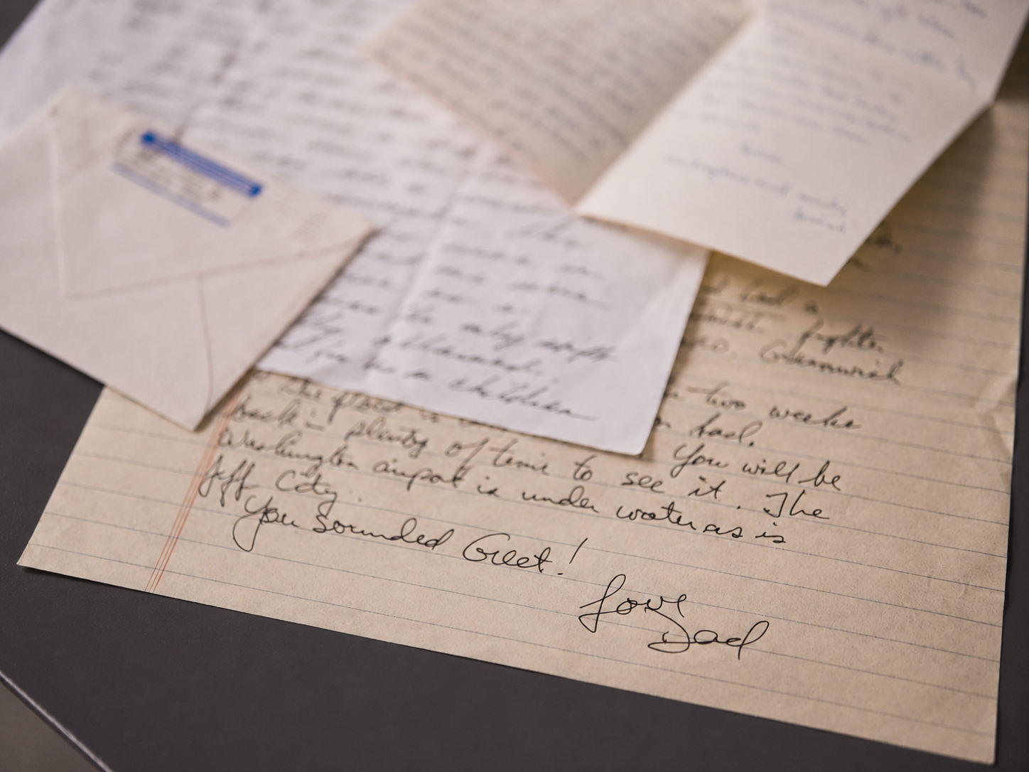 Handwritten family letters and an envelope spread across a desk, signed &ldquo;Love, Dad&rdquo;